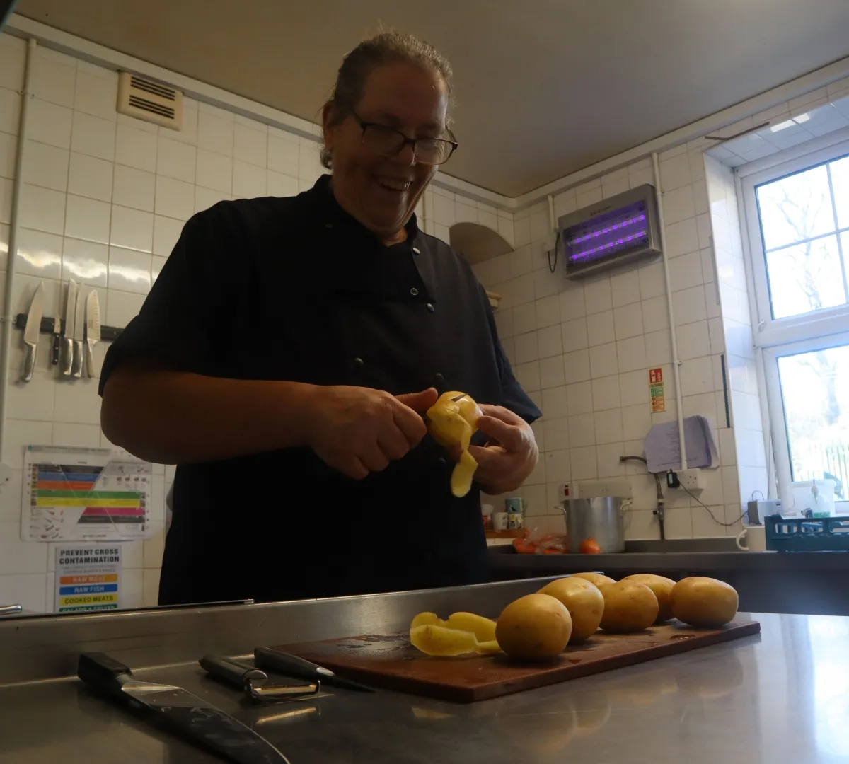 care home kitchen assistant chopping up vegetables