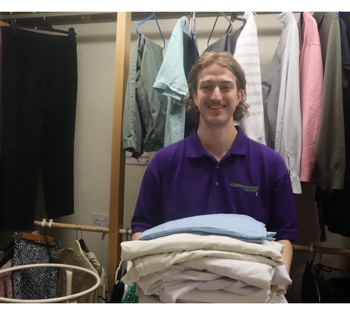 Care Home Housekeeper photographed smiling and holding laundry