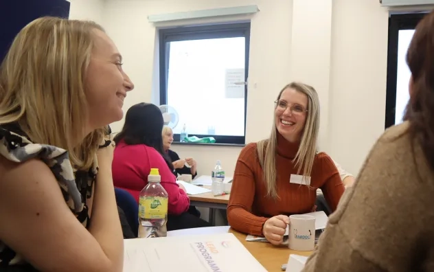 LEAD Programme attendees sat around a table smiling and chatting to each other