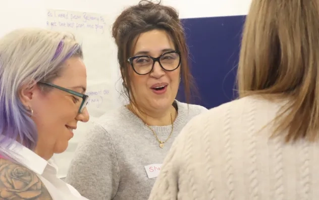 Two LEAD Programme attendees discuss a group task while smiling at each other